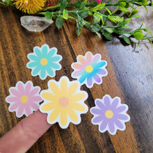Load image into Gallery viewer, picture of 5 multi-colored daisy stickers and yellow daisy stickeron the end of index finger for scale